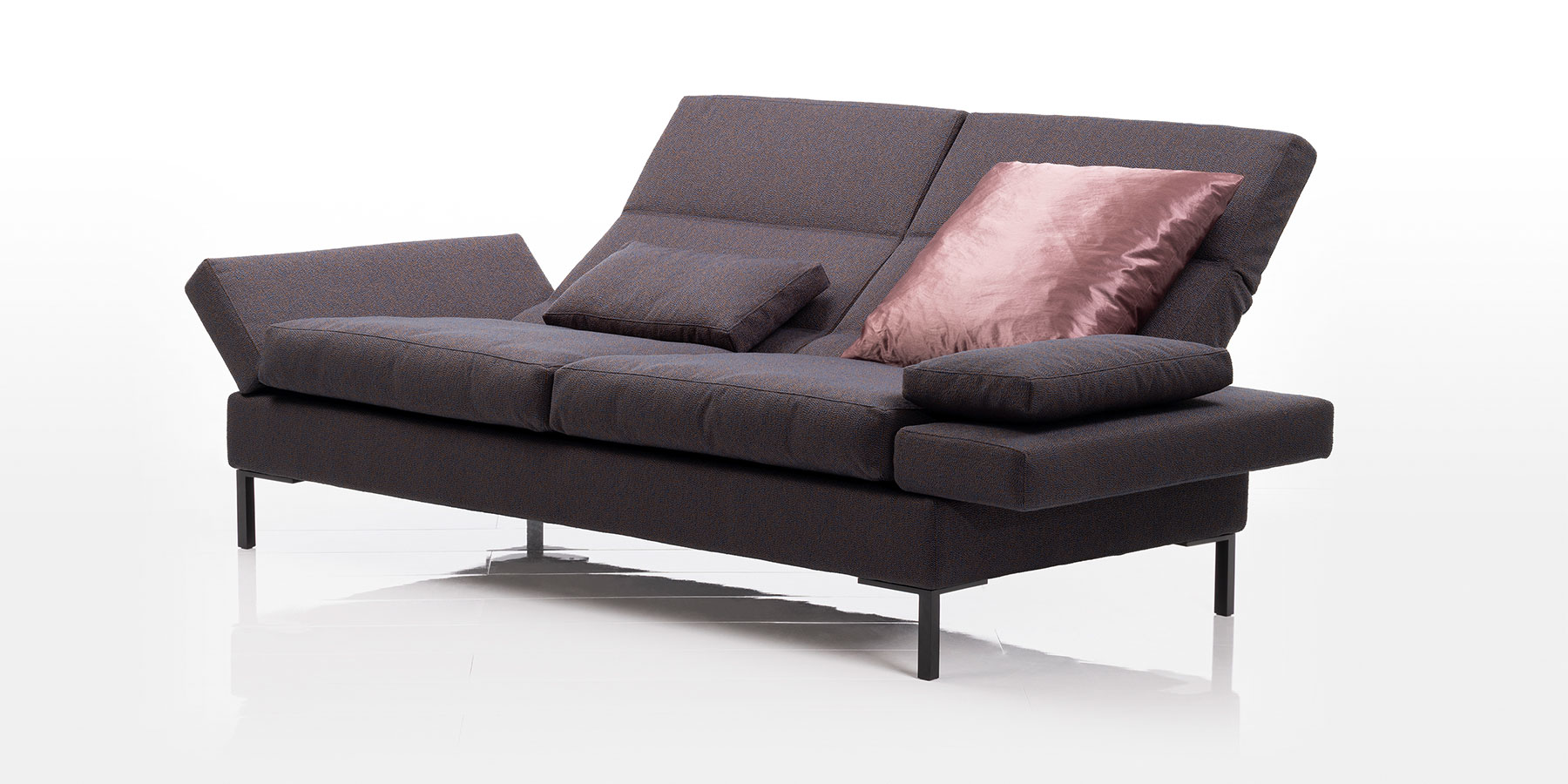 Sofas von brühl Ein Sofa mit zwei Sitzplätzen. Die Armlehnen sind abgeklappt, die Rückenlehnen in leicht geneigter Position.