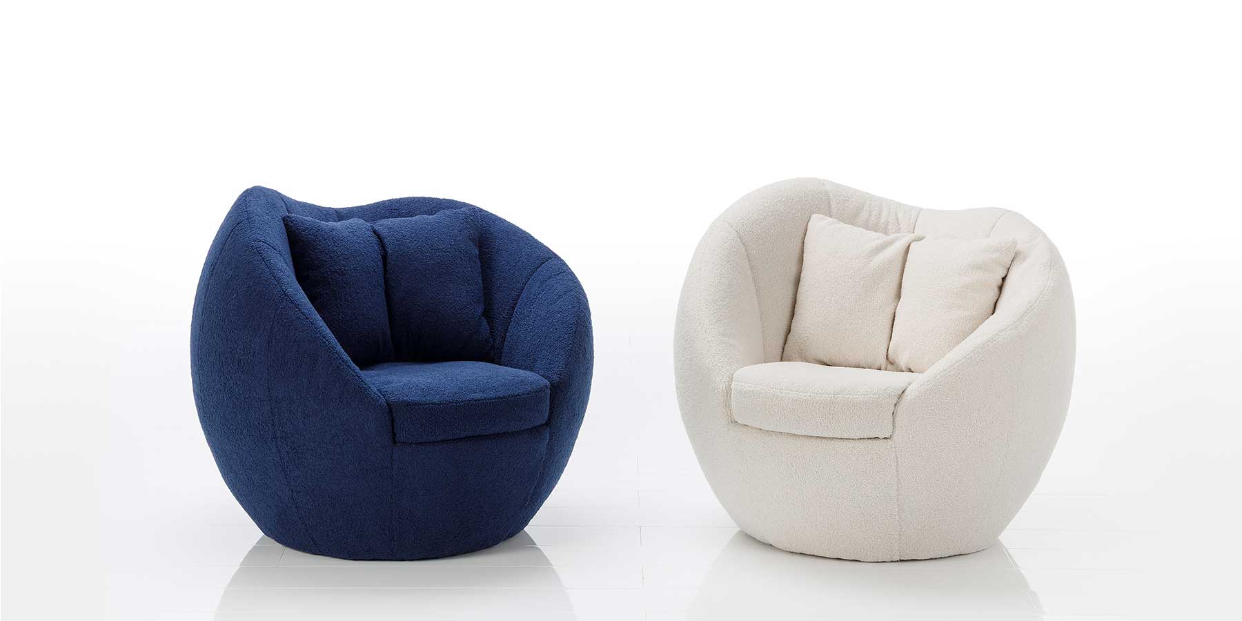 Sessel azur von brühl Zwei Designersessel stehen nebeneinander. Die äußere Form der Sessel ist rund, der Rücken ist oben wellenförmig geschwungen, auf der Sitzfläche liegen je zwei Kissen. Der linke Sessel ist dunkelblau, der linke Sessel ist cremeweiß.