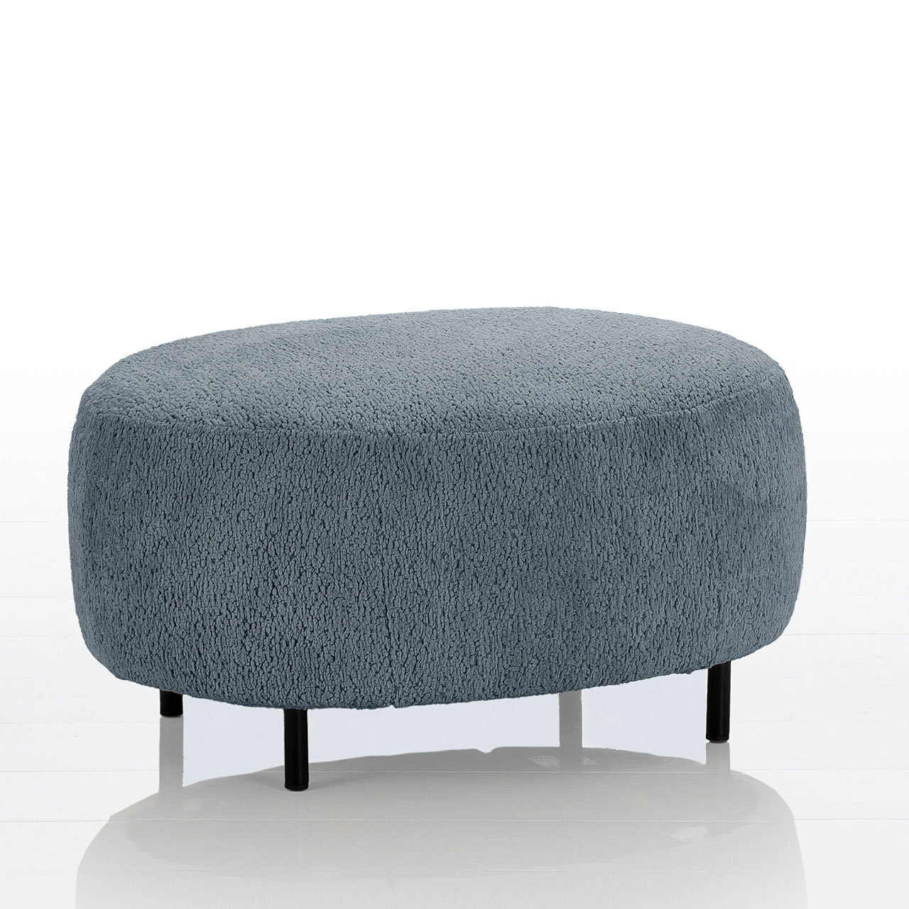 Ovaler Hocker mit schwarzen Metallfüßen. Die Sitzfläche ist in einem blaugrauen Stoff gearbeitet.