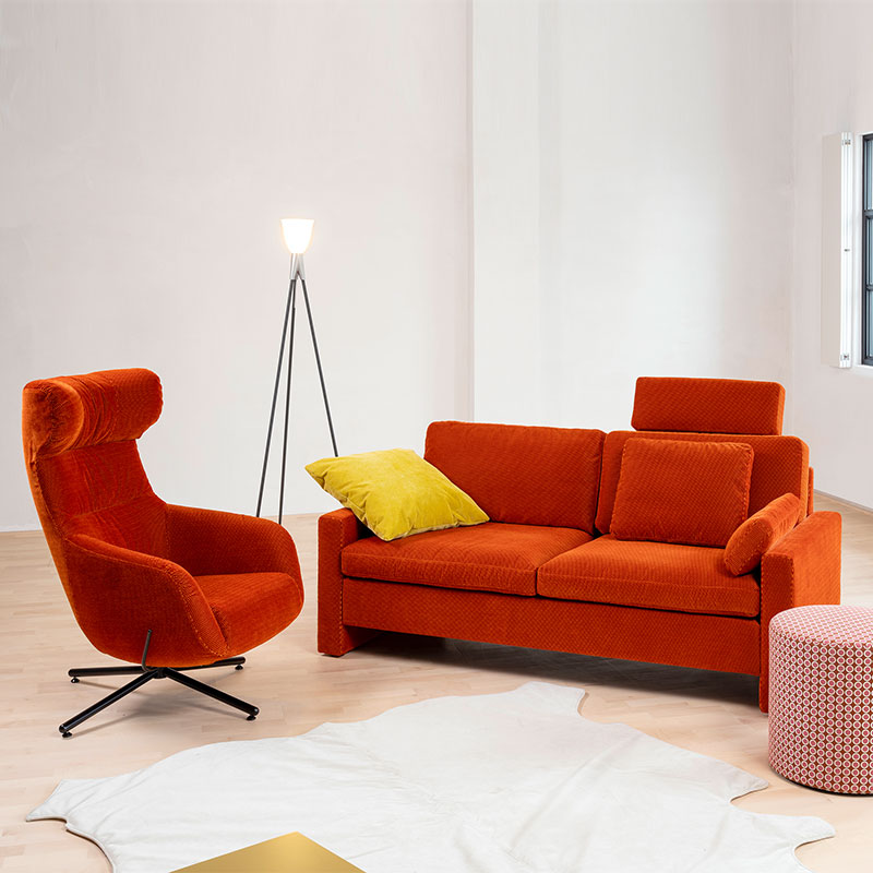 Link: brühl alba system/m Ambientebild mit einer Couch in rostrot und einem Drehsessel in gleicher Farbe.