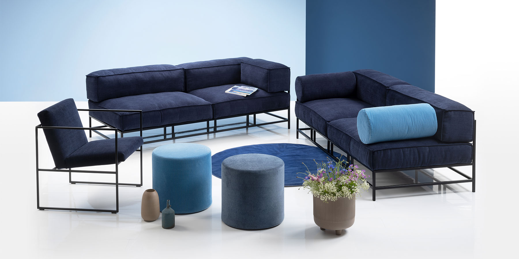 Easy pieces von brühl bestehen nur aus zwei Elementen. Zwei dunkelblaue Openends mit einem filigranen, eckigen, schwarzen Metallgestell stehen zusammen mit einem Sessel in gleicher Farbe.