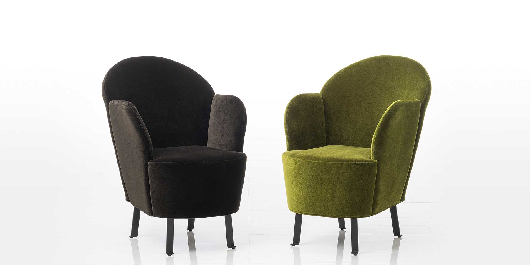 Sessel floret von brühl Zwei Sessel mit Beinen in schwarzem Flachstahl. Der linke Sessel ist mit einem grauschwarzen, der rechte Sessel mit einem moosgrünen Stoff bezogen.