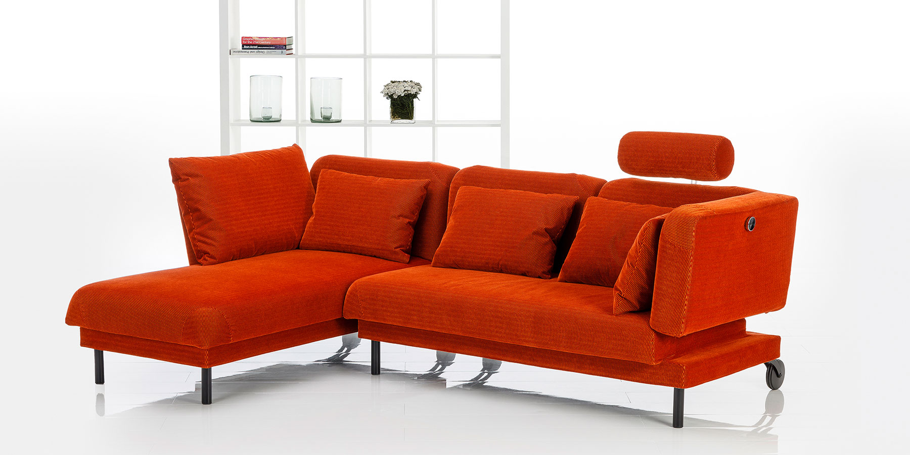 Schlafsofa brühl tam Ein rotes Ecksofa mit aufgesetzter Kopfstütze rechts.