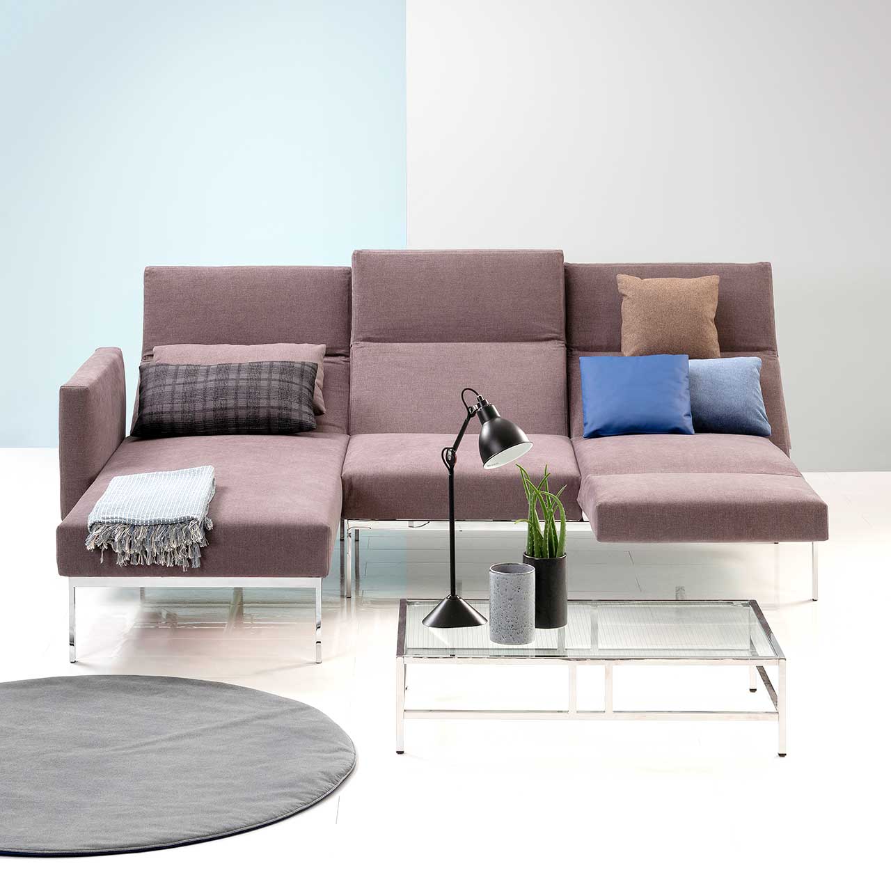 Garnitur brühl roro medium spring 73922 + 73907. Ambientebild Ambientebild der Eckgarnitur der Serie roro medium spring mit Longchair links und Anstellsofa rechts in Stoff. Die Rückenlehnen sind aufgefaltet und zur Relaxposition abgesenkt, die Armlehne rechts ist zur Fußstütze umgeschwenkt.