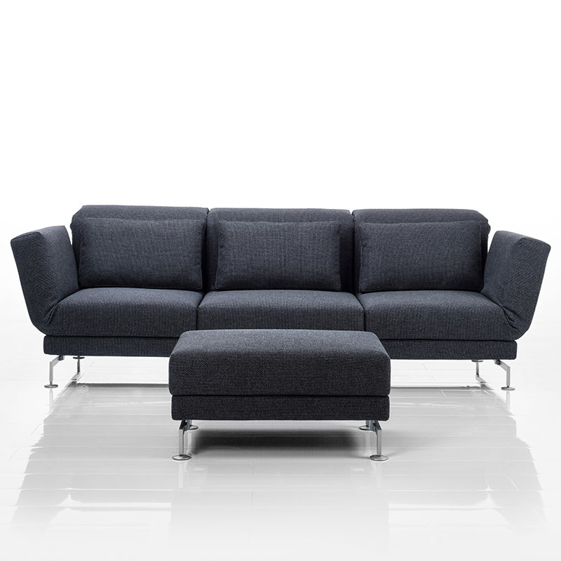 Link: brühl moule medium Sofa mit drei Sitzplätzen in dunkelgrauem Stoff. Vor dem mittleren Sitzplatz steht ein passender Hocker.
