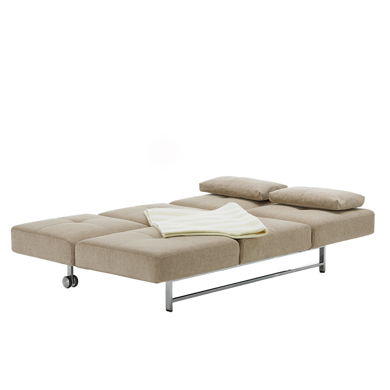 Zur Liegefläche umgeklapptes Bettsofa in einem hellen Braun. Zwei schmale rechteckige Kissen liegen am Kopfende als Kopfkissen. Auf der Liegefläche liegt eine zusammengefaltete Decke.