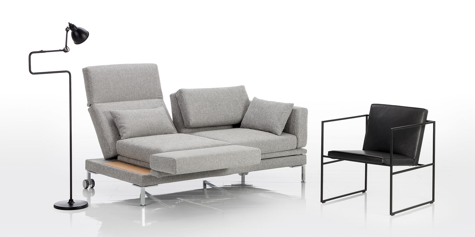 Multifunktionssofa brühl fold out Ein Sofa in grauem Stoff. Die linke Rüclenlehne ist aufgefaltet und leicht abgesenkt. Die linke Armlehne wurde als Fußstütze nach vorne geschwenkt.